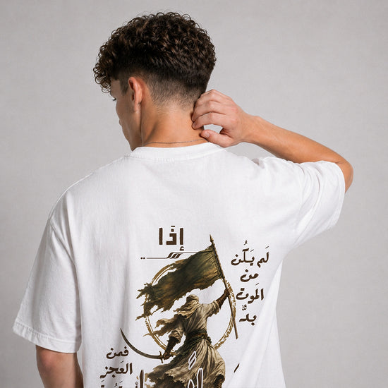 A man viewed from behind wearing a white t-shirt with a large graphic print on the back. The print features Arabic calligraphy and an illustration of a figure holding a flag.
