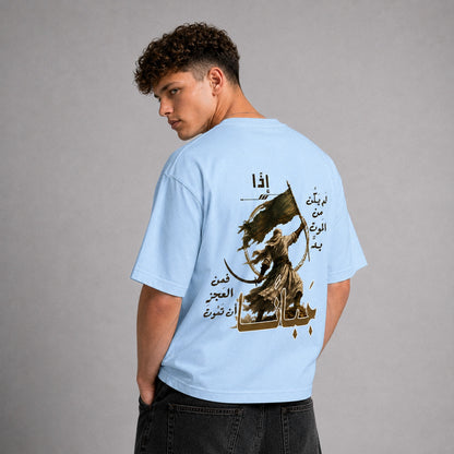 A man wearing a light blue t-shirt with a large graphic print on the back, shown from behind against a neutral gray background.