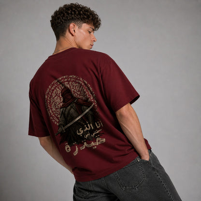 A man wearing a maroon t-shirt with a large graphic print on the back, photographed from behind against a neutral gray background.