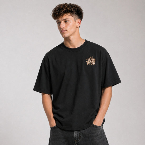 Person wearing a black t-shirt with a small logo on a gray background