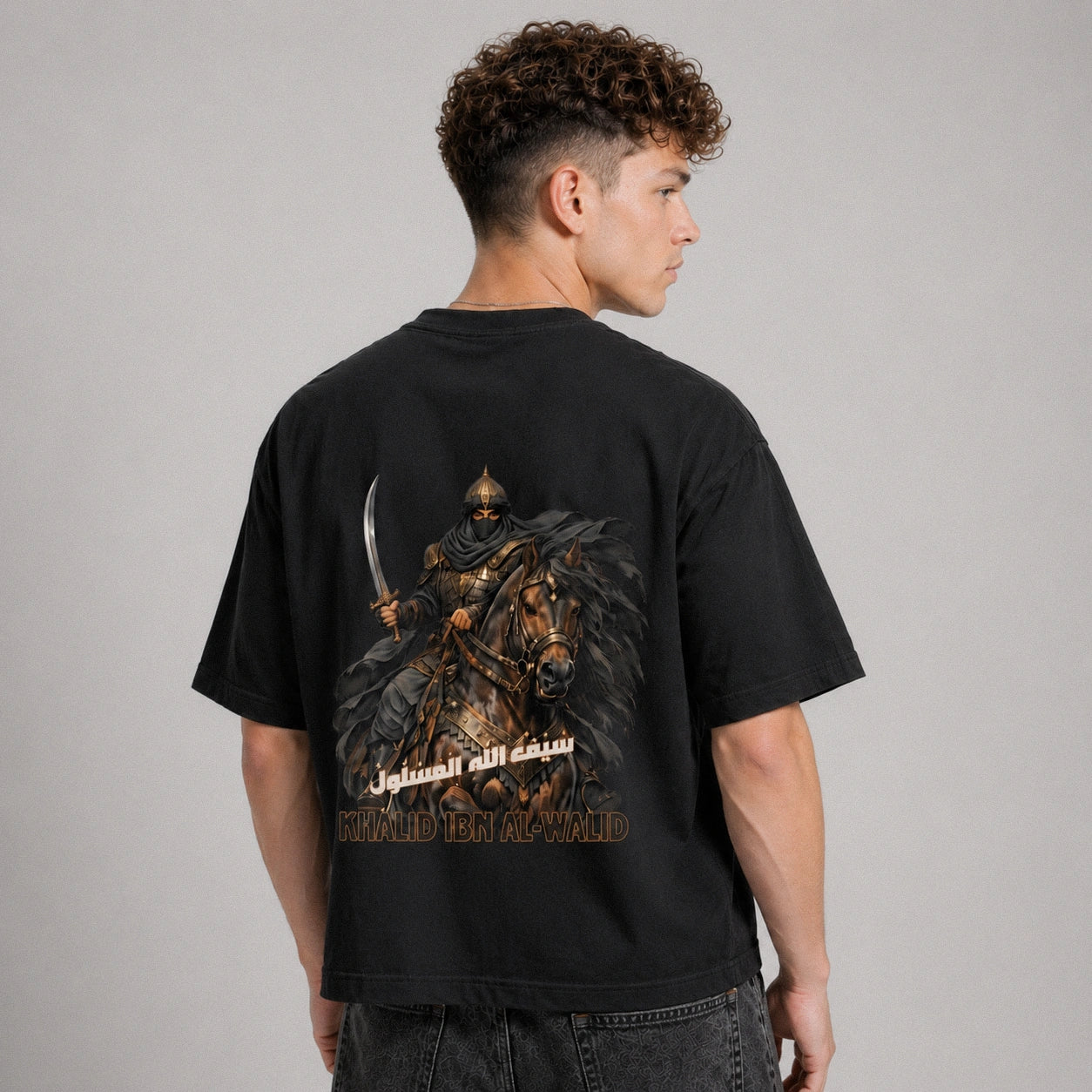 Person wearing a black t-shirt with a graphic design on the back, standing against a plain background.
