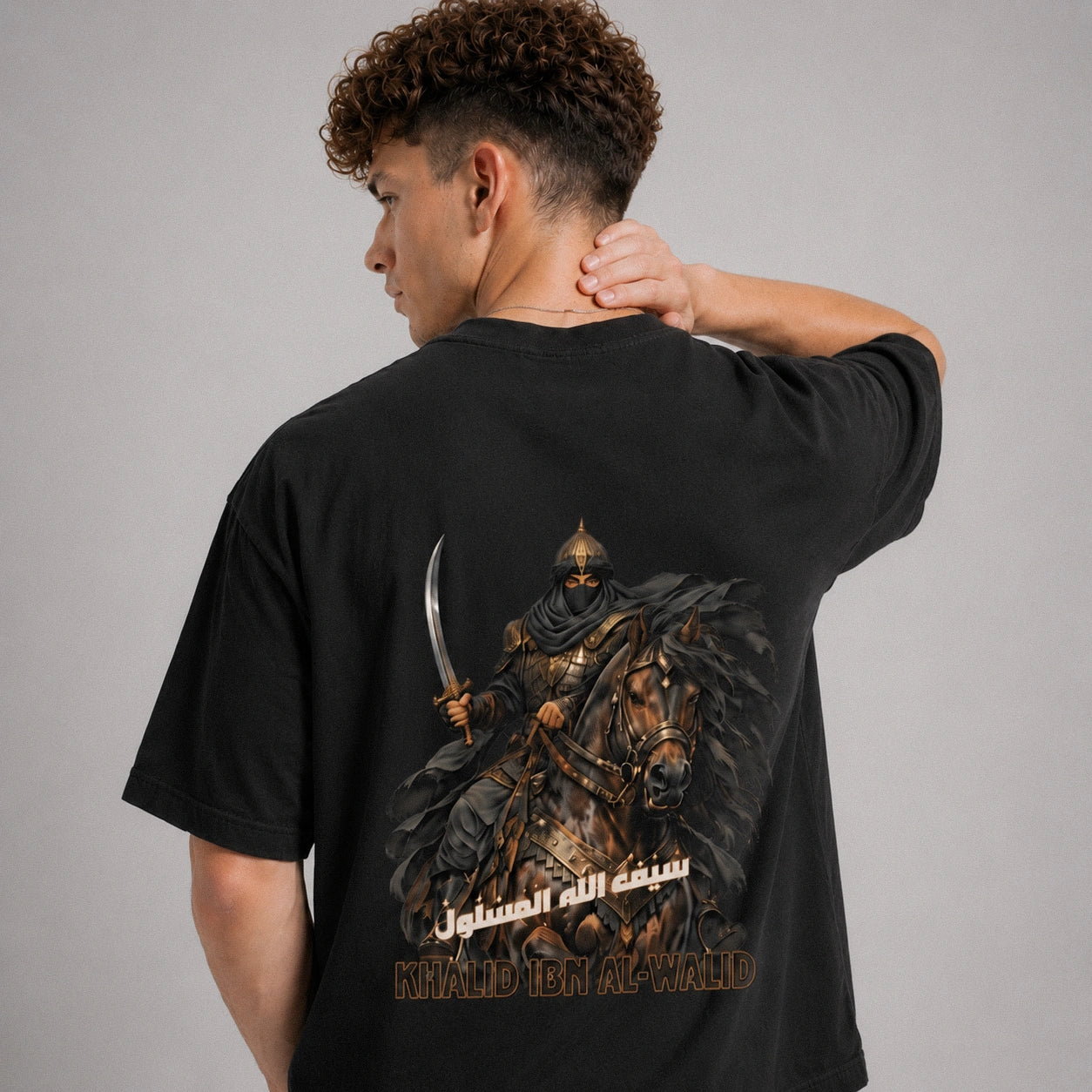 Person wearing a black t-shirt with a graphic design on the back, featuring a warrior on a horse.