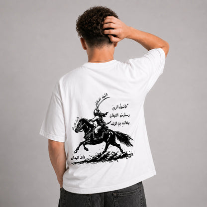 Man wearing a black t-shirt with Arabic text on a gray background