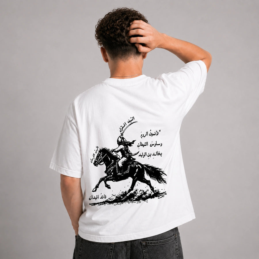 Man wearing a black t-shirt with Arabic text on a gray background