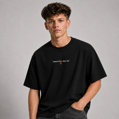 Man wearing a black t-shirt with text and a red heart symbol on a gray background