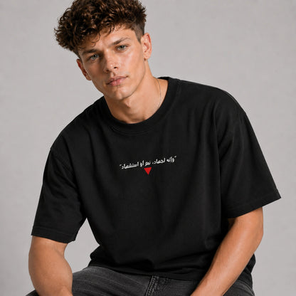 Man wearing a black t-shirt with Arabic text and a red heart on a gray background
