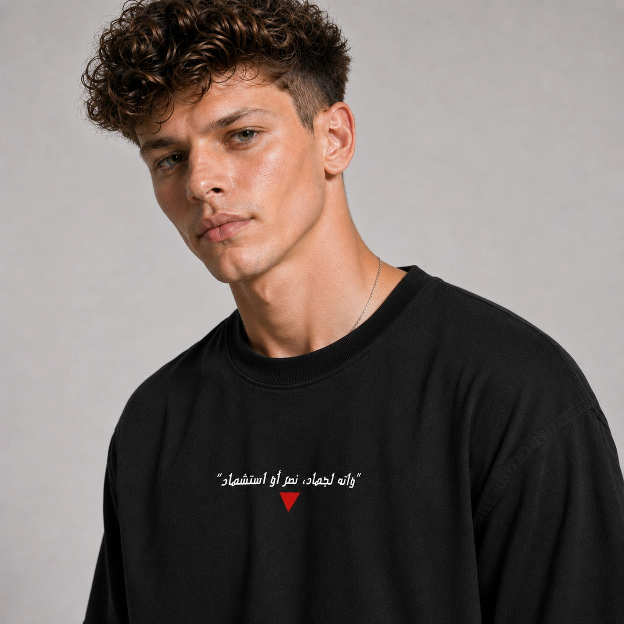 Man wearing a black sweatshirt with Arabic text and a red heart symbol on a gray background