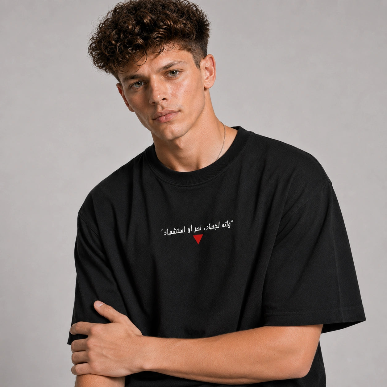 Person wearing a black t-shirt with Arabic text and a red heart on a gray background