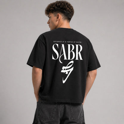 Person wearing a black t-shirt with 'SABR' logo and text on the back, standing against a gray background