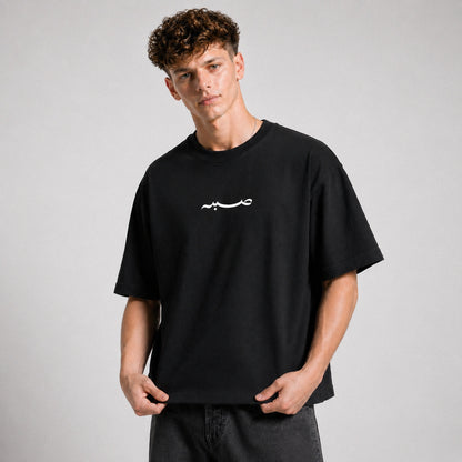Person wearing a black t-shirt with a white logo on a gray background