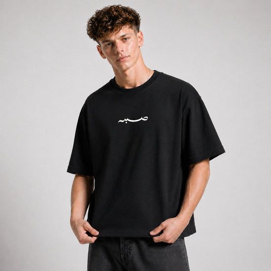 Person wearing a black t-shirt with a white logo on a gray background