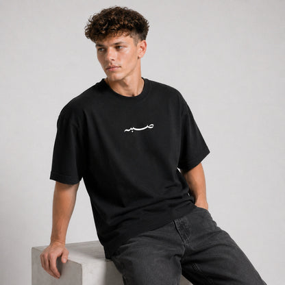 Man wearing a black t-shirt with a white logo on a gray background