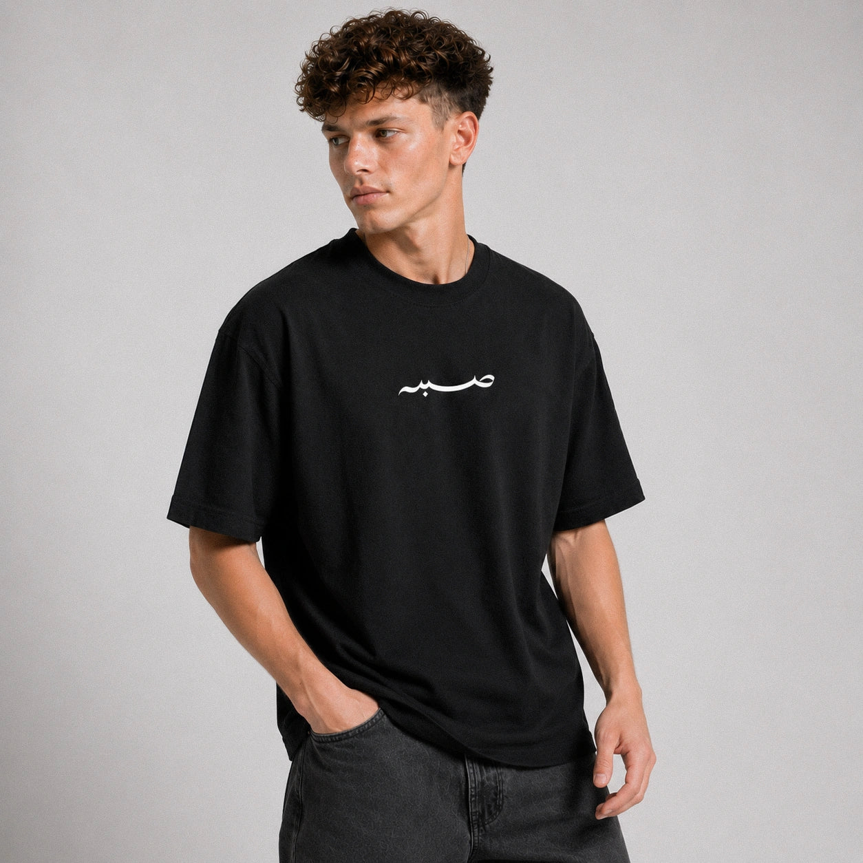 Man wearing a black t-shirt with a white logo on a gray background