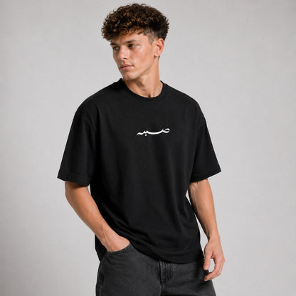 Man wearing a black t-shirt with a white logo on a gray background