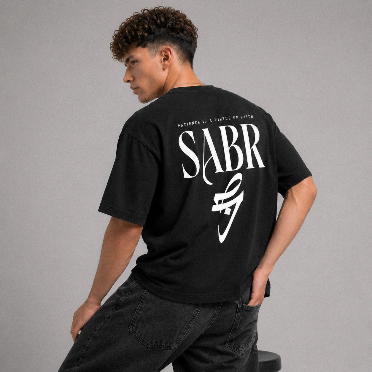 Person wearing a black t-shirt with 'SABR' printed on the back against a gray background