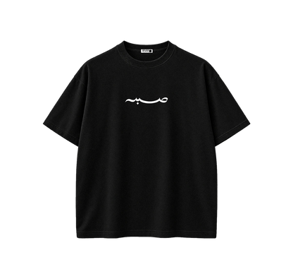 A black short-sleeve crewneck t-shirt with a white Arabic calligraphy graphic printed across the chest, displayed on a clean white background.