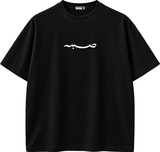 A black short-sleeve crewneck t-shirt with a white Arabic calligraphy graphic printed across the chest, displayed on a clean white background.