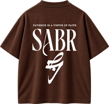 A brown short-sleeve t-shirt shown from the back, featuring a large white graphic print with the text 'PATIENCE IS A VIRTUE OF FAITH' and 'SABR' above a stylized white logo.