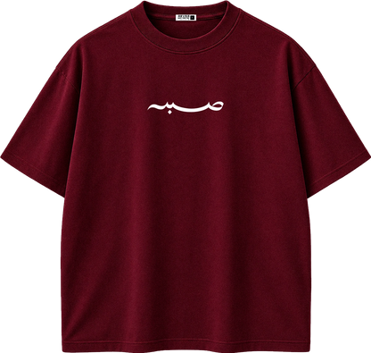 A dark red crewneck t-shirt with white Arabic calligraphy printed on the chest, displayed on a clean white background.
