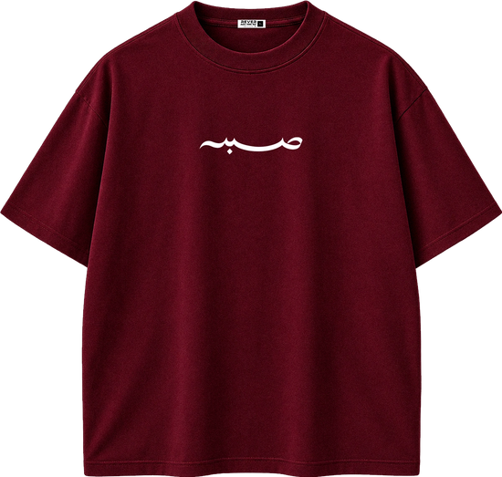 A dark red crewneck t-shirt with white Arabic calligraphy printed on the chest, displayed on a clean white background.