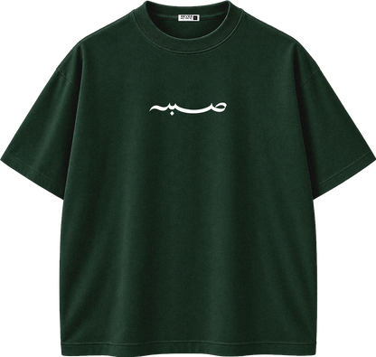 A dark forest green short-sleeve crewneck t-shirt with a white Arabic calligraphy graphic printed across the chest, displayed on a clean white background.