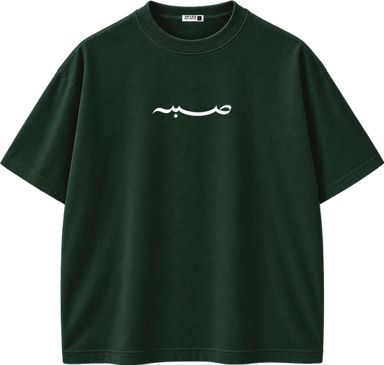 A dark forest green short-sleeve crewneck t-shirt with a white Arabic calligraphy graphic printed across the chest, displayed on a clean white background.