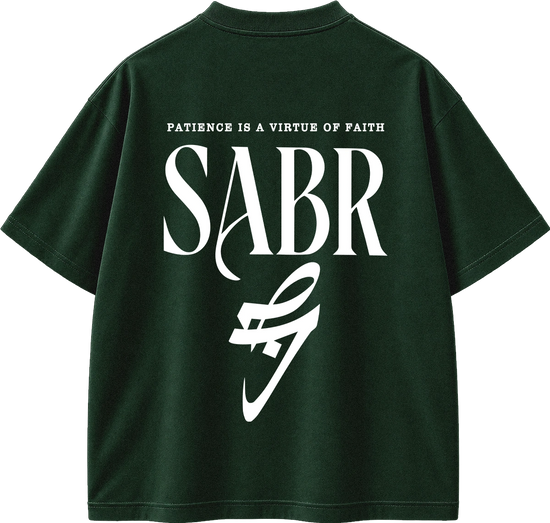 A dark forest green short-sleeve t-shirt shown from the back, featuring a large white graphic print with the text 'PATIENCE IS A VIRTUE OF FAITH' and 'SABR' in a stylized serif font, with a white abstract swoosh-like graphic below.