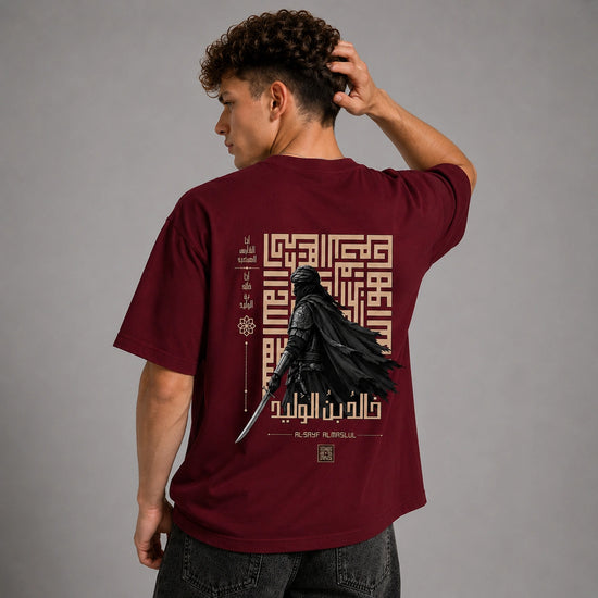 A man wearing a maroon t-shirt from the back, featuring a large graphic print of Darth Vader with a lightsaber and Arabic calligraphy on a gray studio background.