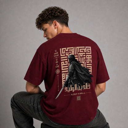 A man wearing a maroon t-shirt with a large graphic print on the back, shown from behind in a studio setting.