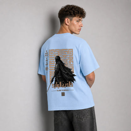 A man wearing a light blue t-shirt with a large Darth Vader graphic on the back, shown from behind against a neutral gray background.