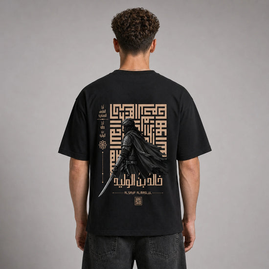 A man viewed from behind wearing a black t-shirt with a large graphic print on the back. The graphic features a dark knight in a flowing cape holding a sword, set against a beige geometric maze and Arabic calligraphy.