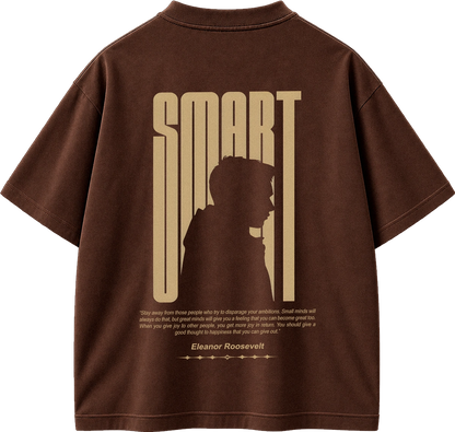 A brown short-sleeve t-shirt shown from the back, featuring a large beige graphic print of the word 'SMART' with a silhouette of a person inside the letters, and a quote attributed to Eleanor Roosevelt below.