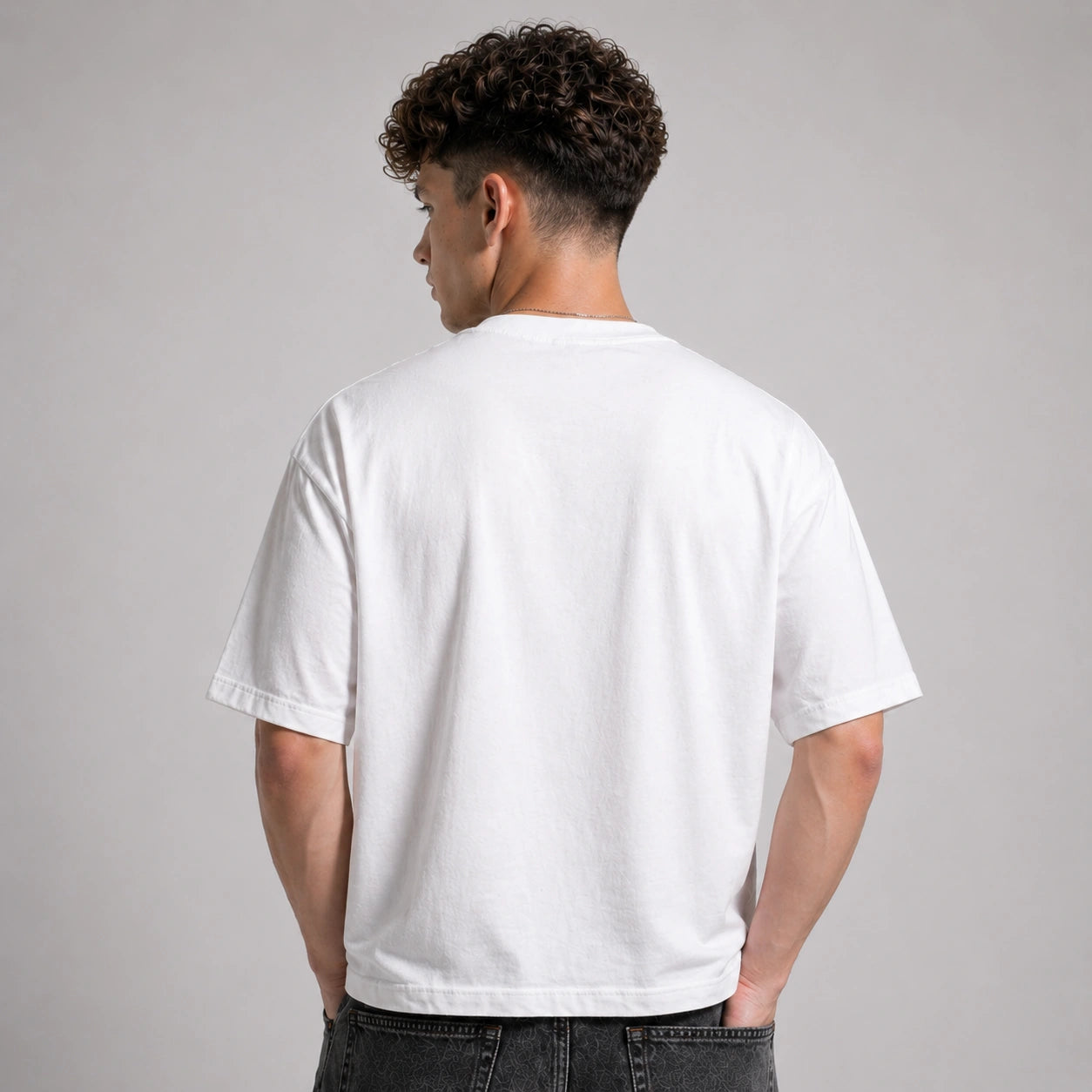 Person wearing a plain white t-shirt against a gray background