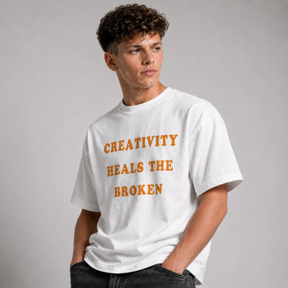 Man wearing a white t-shirt with 'CREATIVITY HEALS THE BROKEN' text on a gray background