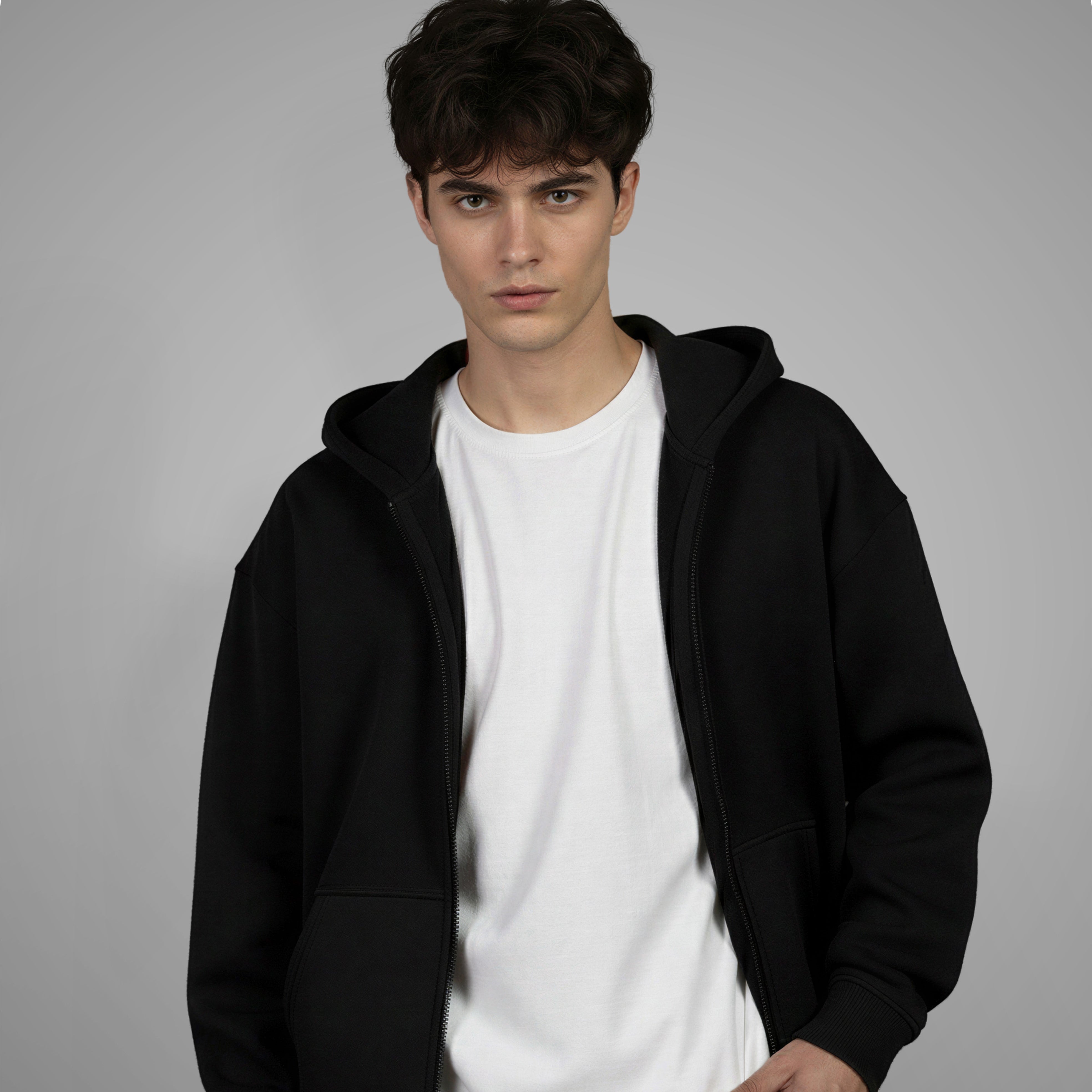 Man wearing a black hoodie over a white shirt on a gray background