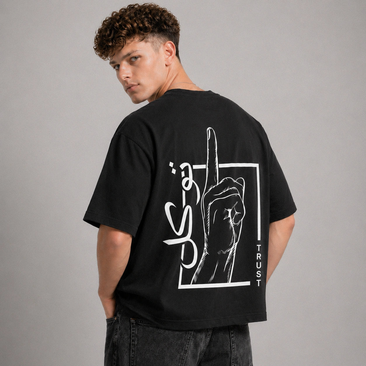 Person wearing a black t-shirt with white graphic design on the back against a gray background