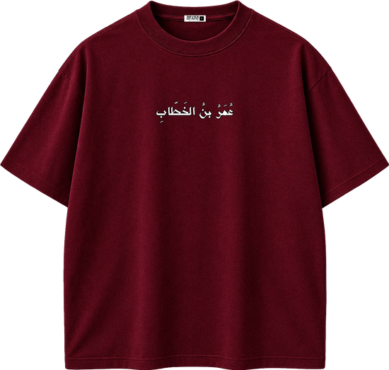 A dark red crewneck t-shirt with a beige Arabic calligraphy graphic printed on the chest, displayed on a clean white background.