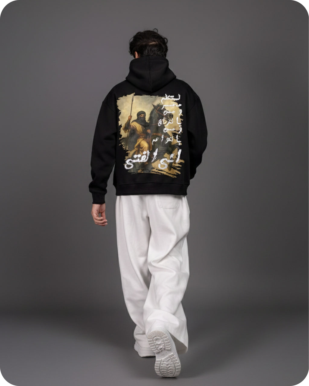 Person wearing a black hoodie with a graphic design on the back against a gray background