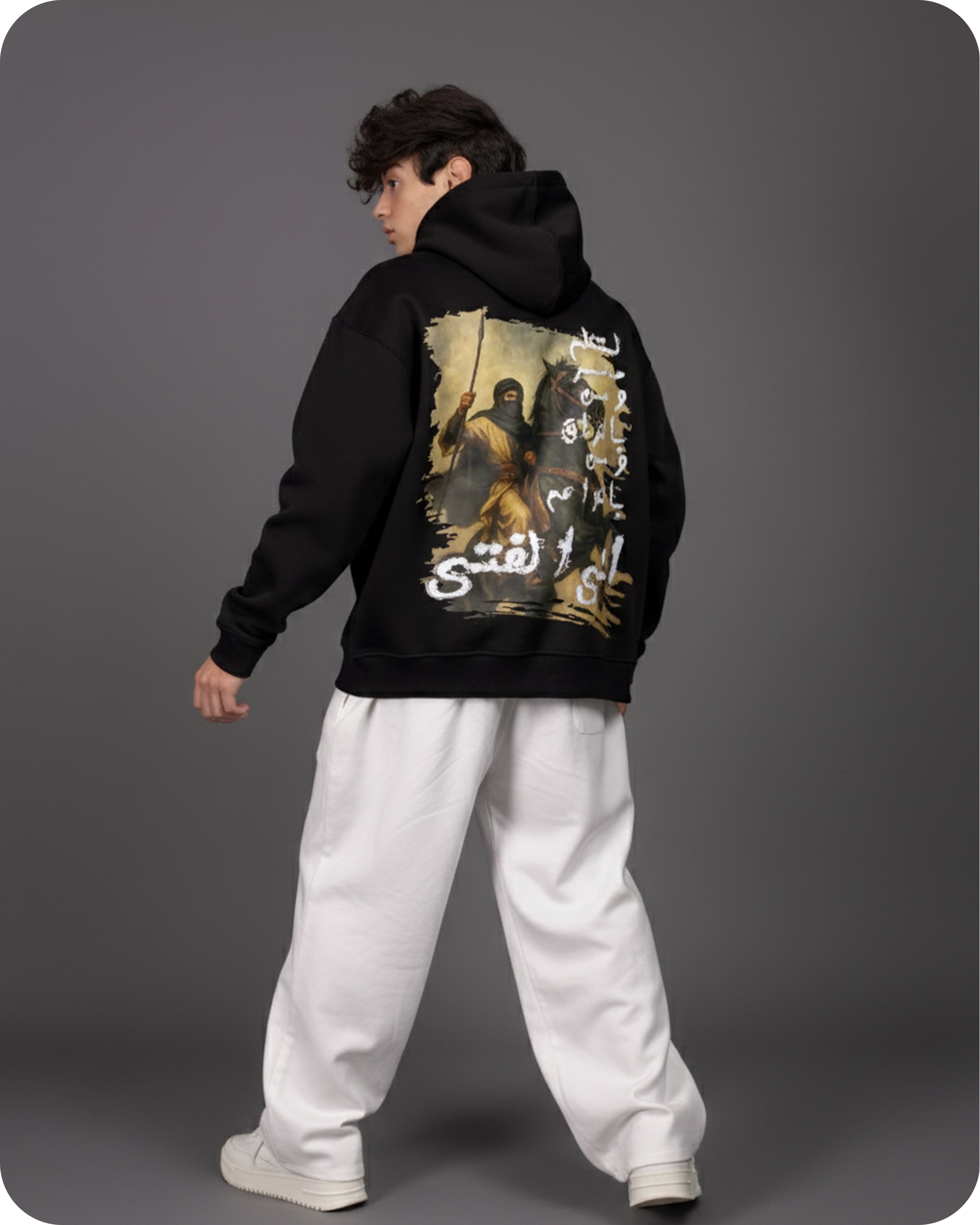 Person wearing a black hoodie with a graphic design on the back against a gray background