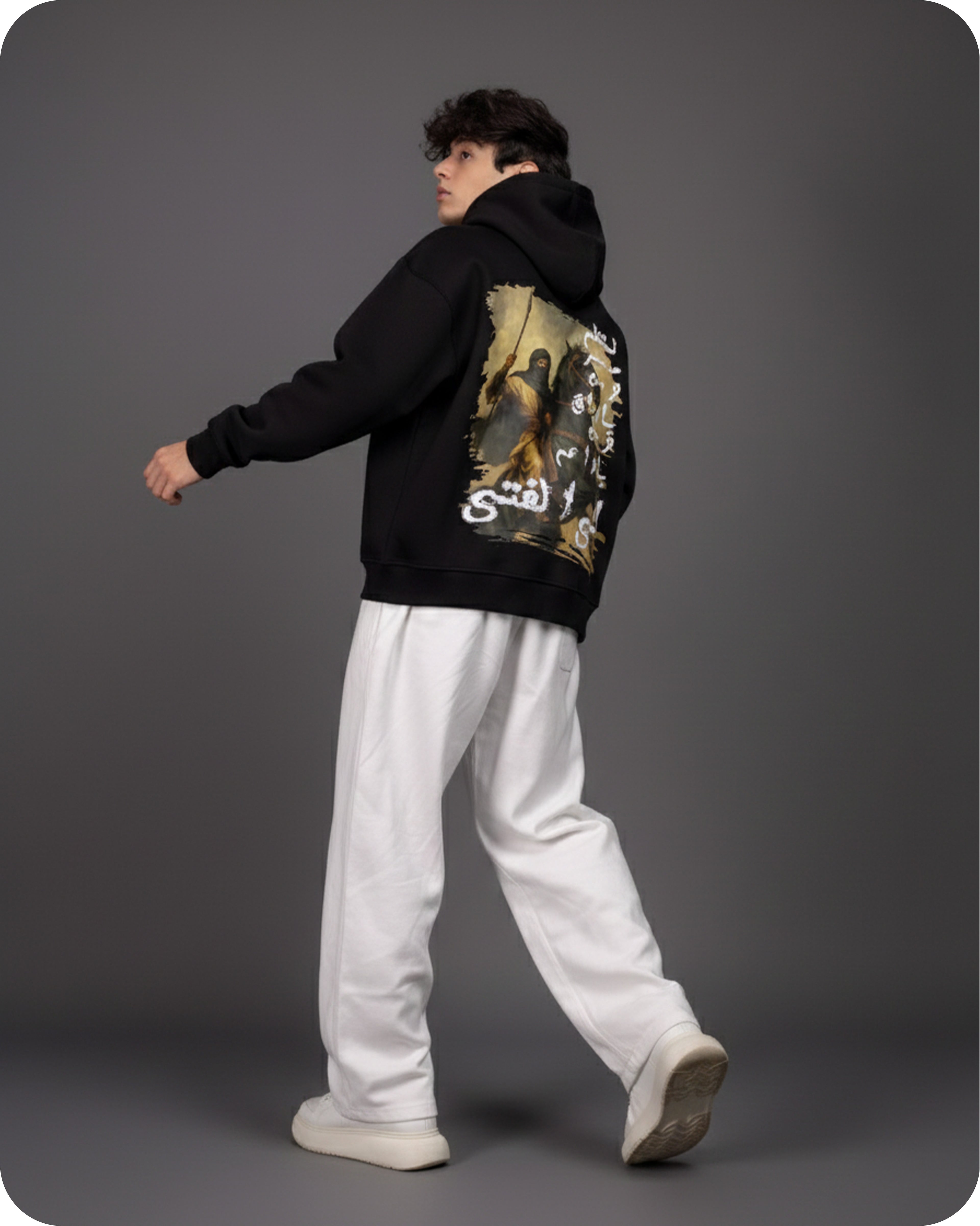 Person wearing a black hoodie with a graphic design on the back against a gray background