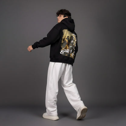 Person wearing a black hoodie with a graphic design on the back against a gray background