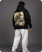 Person wearing a black hoodie with a graphic design on the back against a gray background