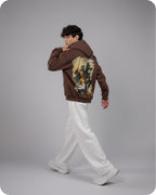 Person wearing a brown hoodie with a graphic design on a gray background