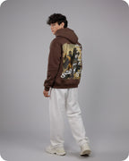 Person wearing a brown hoodie with graphic designs on the back against a gray background