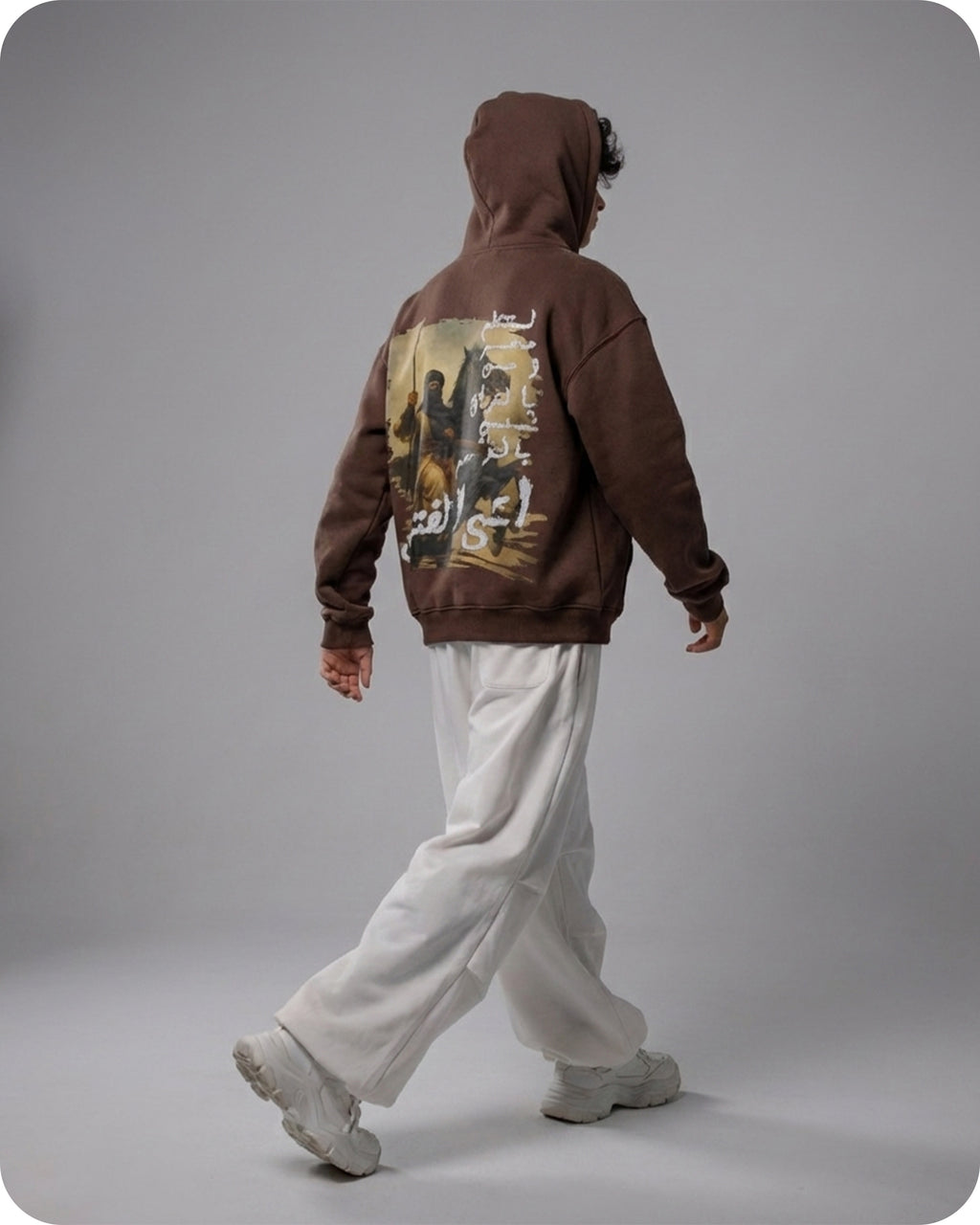 Person wearing a brown hoodie with a graphic design on the back against a gray background