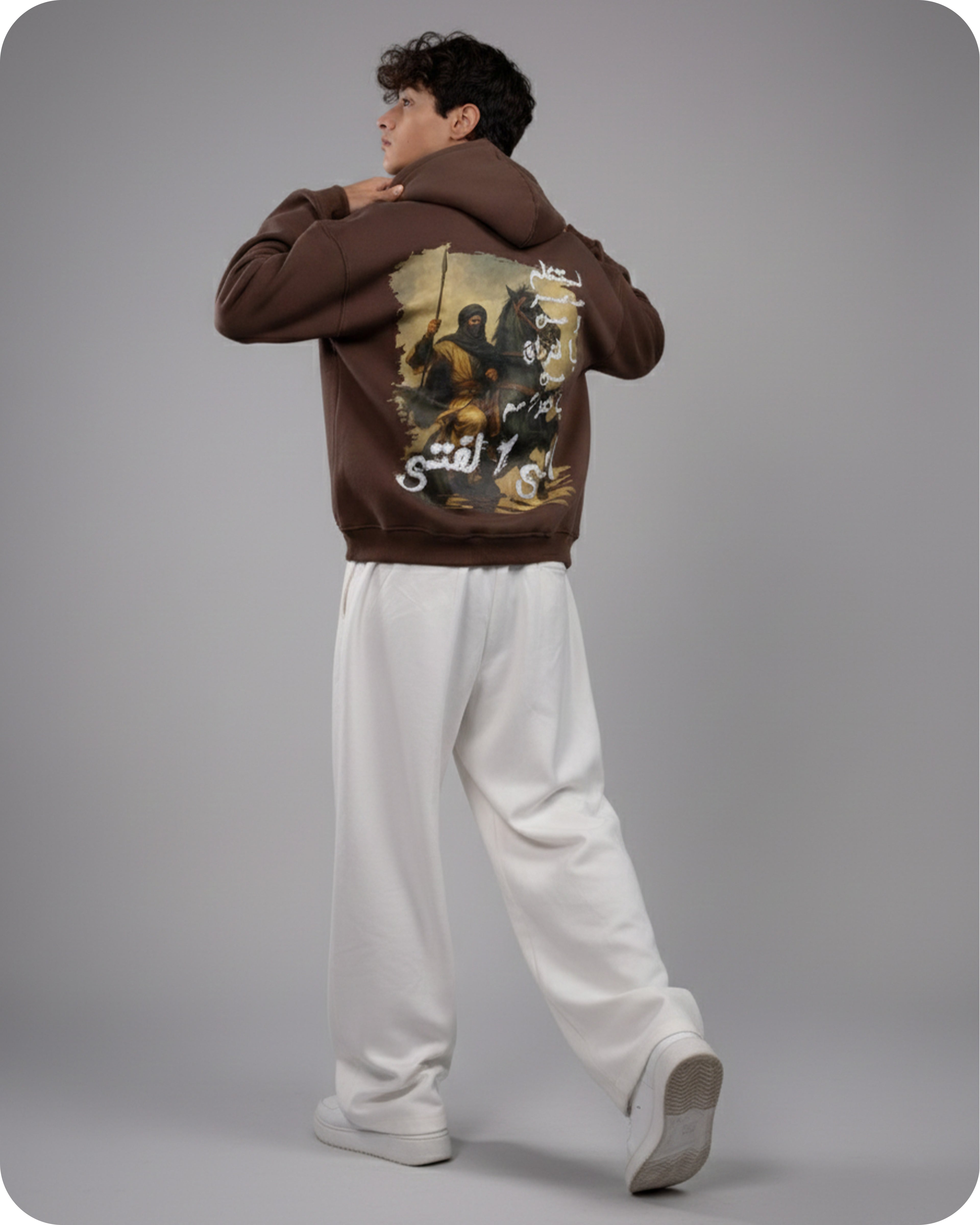 Person wearing a brown hoodie with graphic design on the back against a gray background
