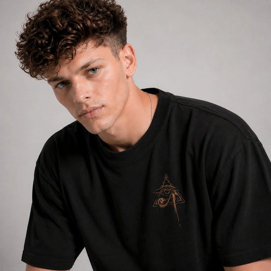 Man wearing a black t-shirt with a logo on a gray background