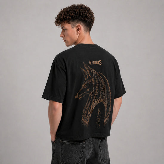 Person wearing a black t-shirt with a dragon design on the back against a gray background