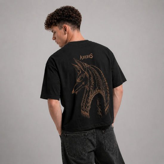 Person wearing a black t-shirt with a wolf skeleton design on the back, standing against a gray background.
