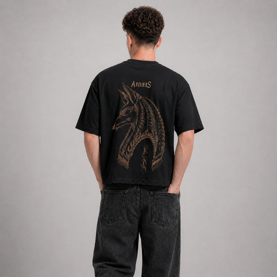 Person wearing a black t-shirt with a dragon design on the back against a gray background
